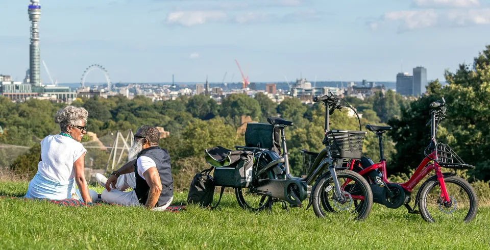 Couple sitting on grass next to their Tern NBD e-bikes