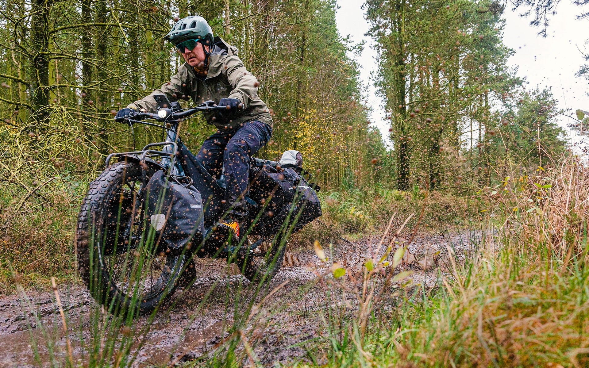 Man riding muddy road on Tern Orox