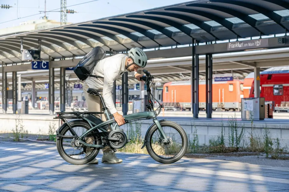 Man on train station platform folding Tern Vektron e-bike