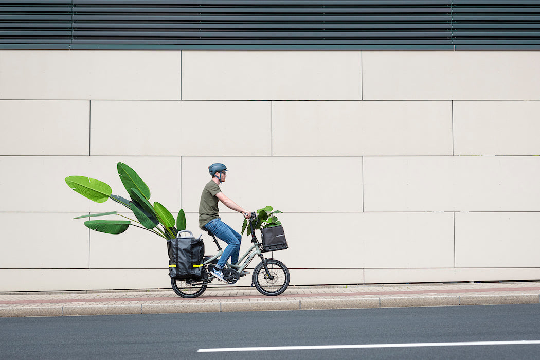 Person riding a Tern electric bicycle with plants on a city street