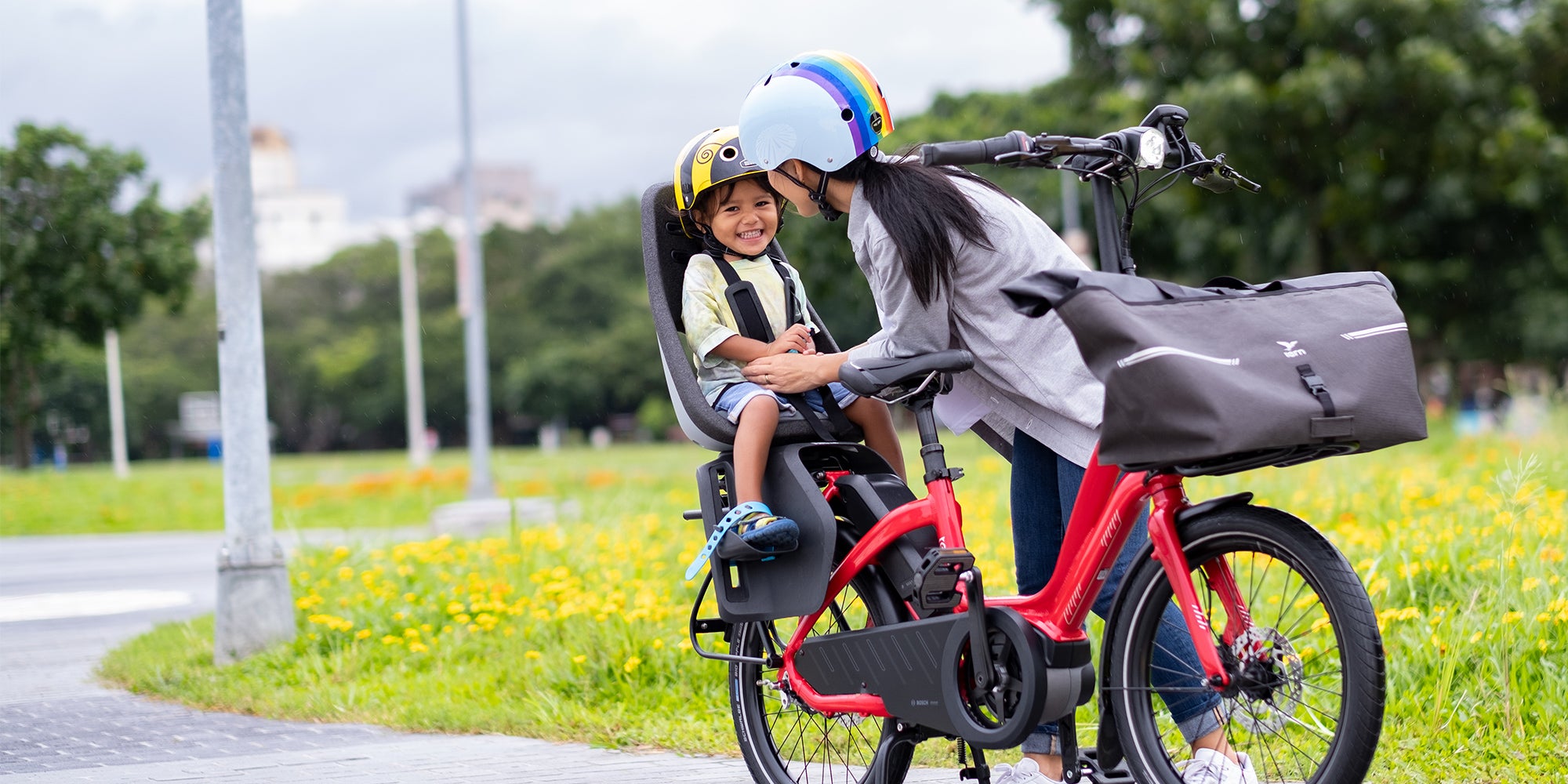 Woman secures child in seat on back of Tern NBD e-bike